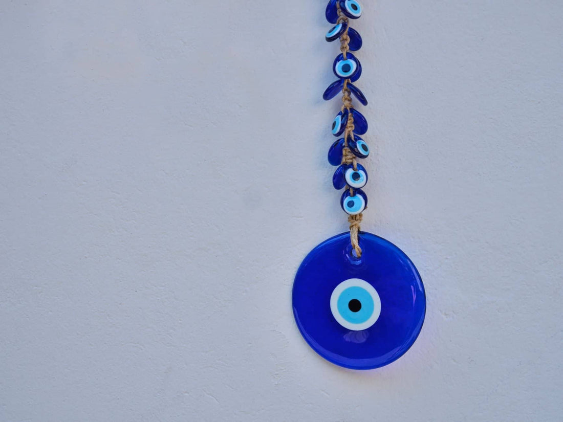 A blue glass evil eye amulet hanging, contrasted with the idea of ambient negative energy