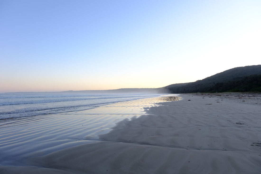 Ocean waves at low tide on a grey morning, wide deserted beach, the tidal law of Hermetic Rhythm