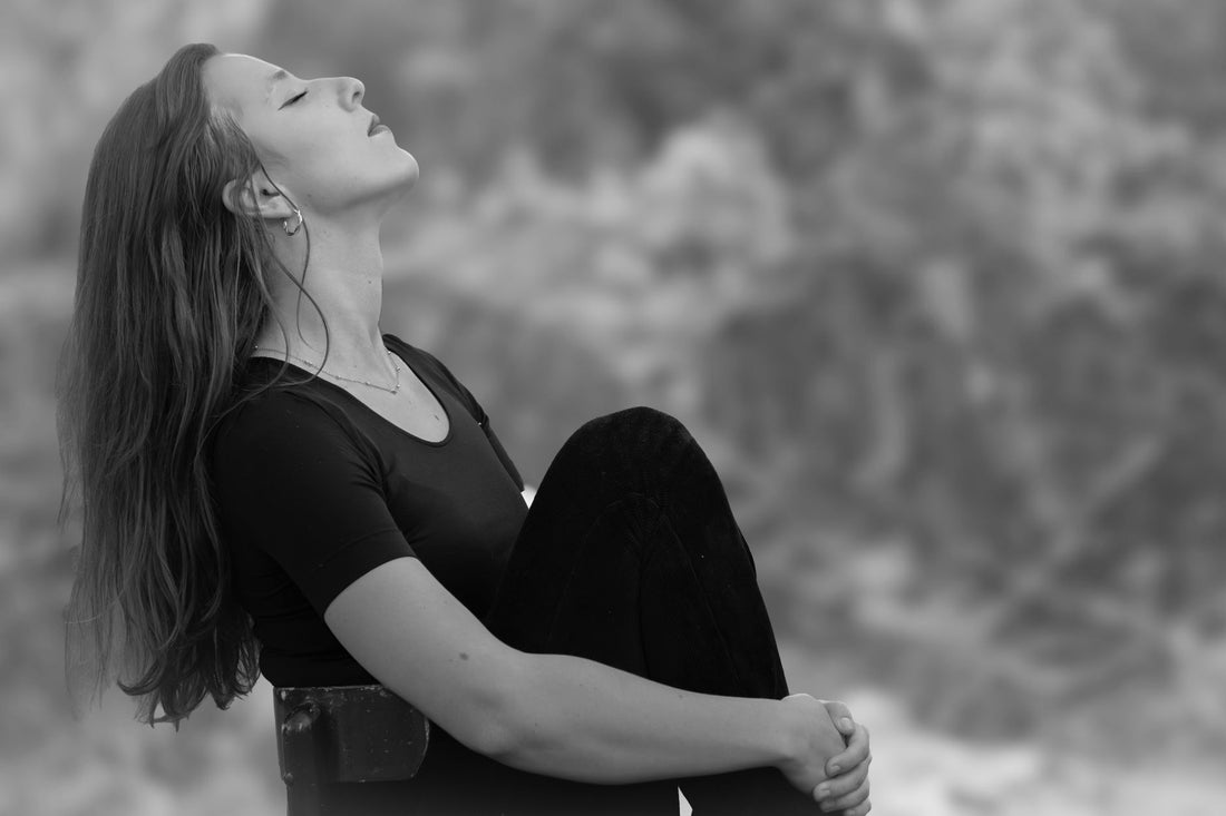 A person sitting peacefully outdoors in nature, breathing deeply during a meditative practice