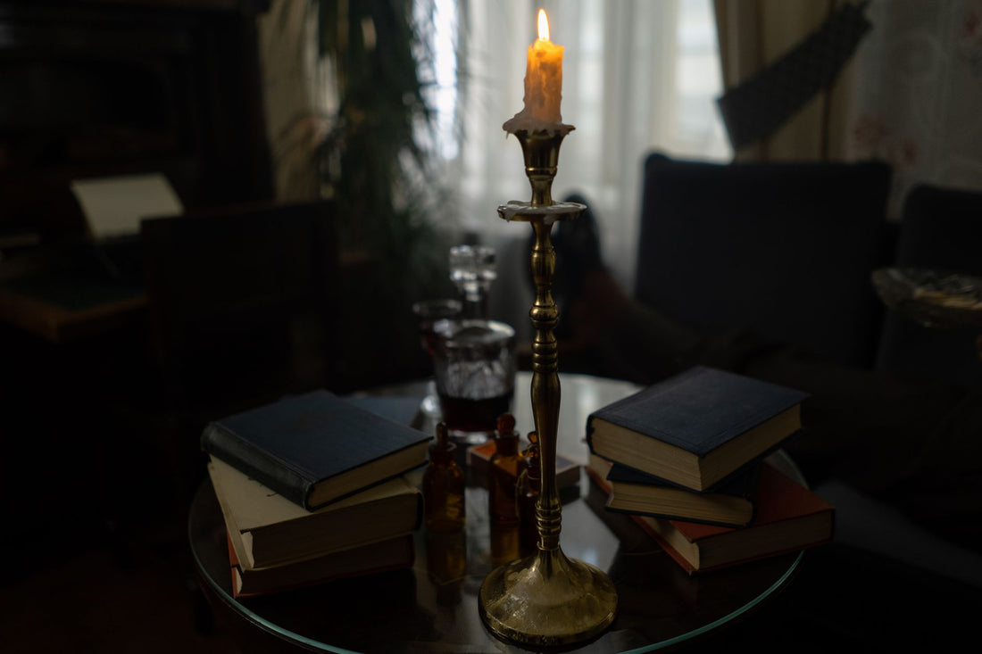 A lighted candle on a gold candle holder, illustrating the Kybalion as a written distillation of Hermetic doctrine
