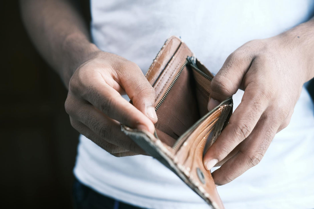 A hand holding an empty open wallet against a neutral backdrop, conveying the sudden unexplained financial loss that the article diagnoses