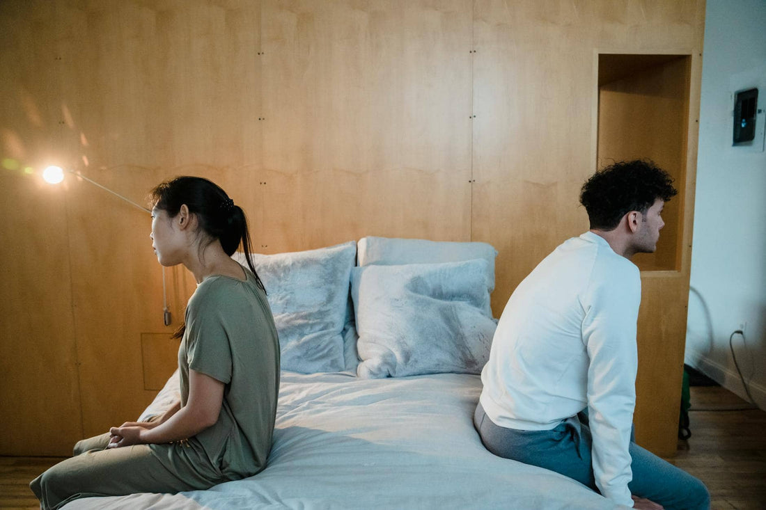 A couple sitting apart on opposite sides of a bed — breaking relationship patterns